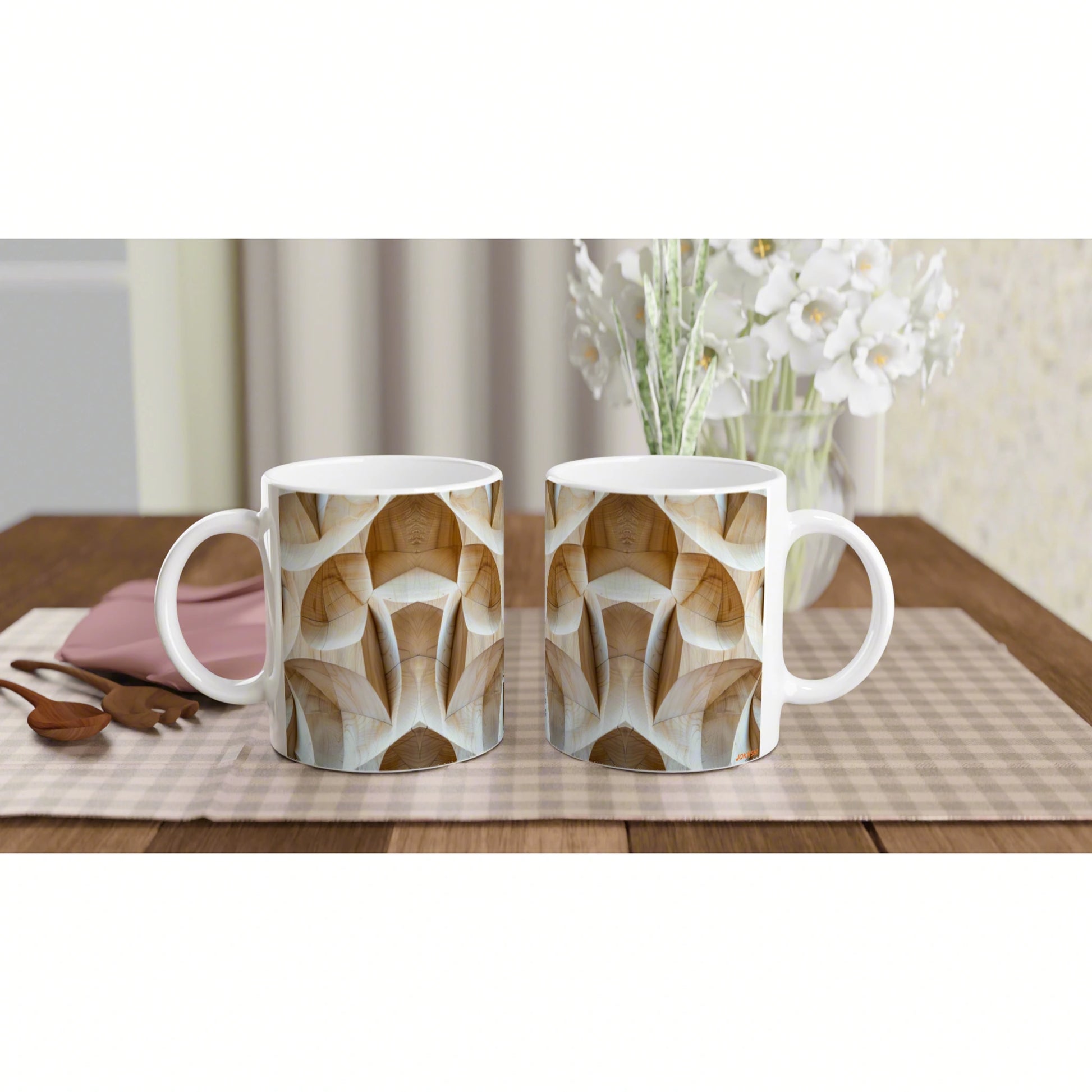 Two white ceramic mugs with beige geometric woodgrain pattern on a checkered table runner, white flowers in background.