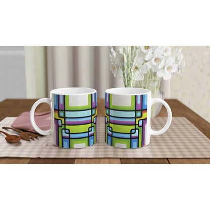 Two white ceramic mugs with a bright geometric multicolor pattern on a wooden table, placed on a plaid placemat with white flowers in the background.