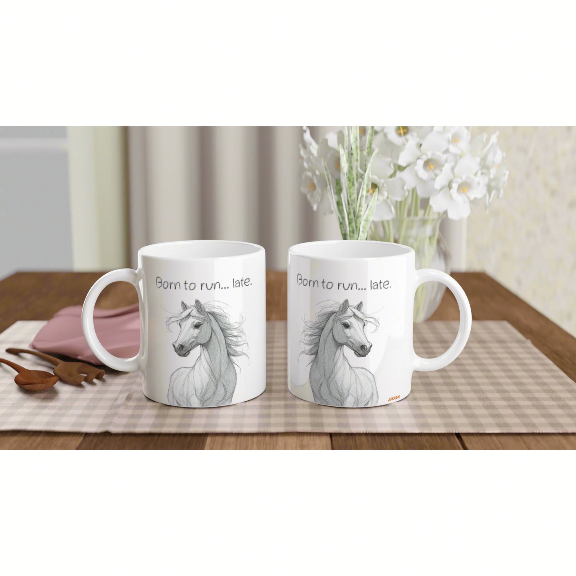 Two white ceramic mugs with a gray horse sketch and the caption Born to run... late on checkered placemat on a wooden table.