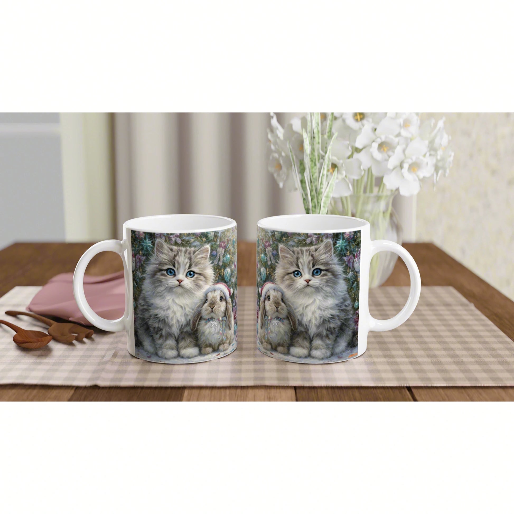 Product mockup: two white ceramic mugs with a kitten and bunny print on a plaid table runner, floral backdrop.