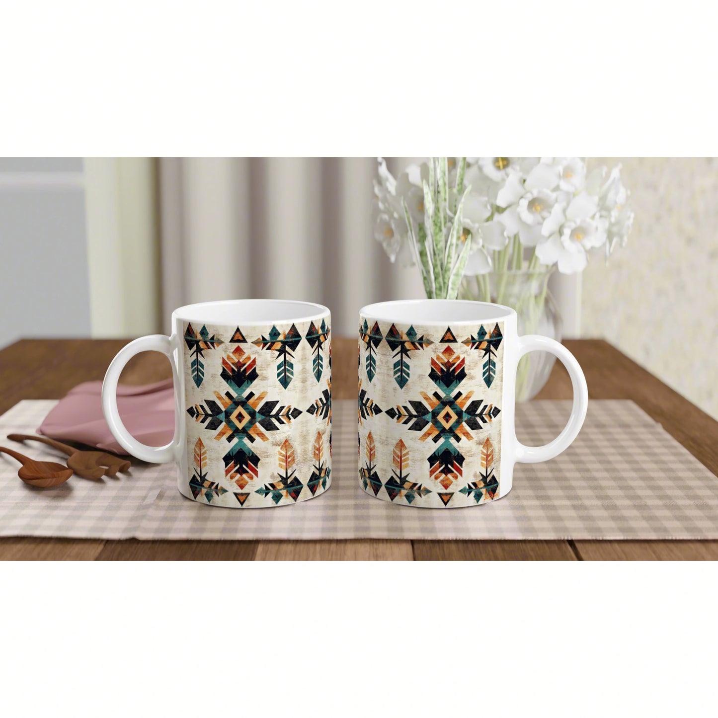 Two white ceramic mugs with teal, orange and black geometric tribal pattern on a wooden table.