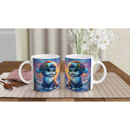 Two white mugs feature a blue fluffy kitten wearing a flower crown, set against a colorful winter backdrop on a wooden table.