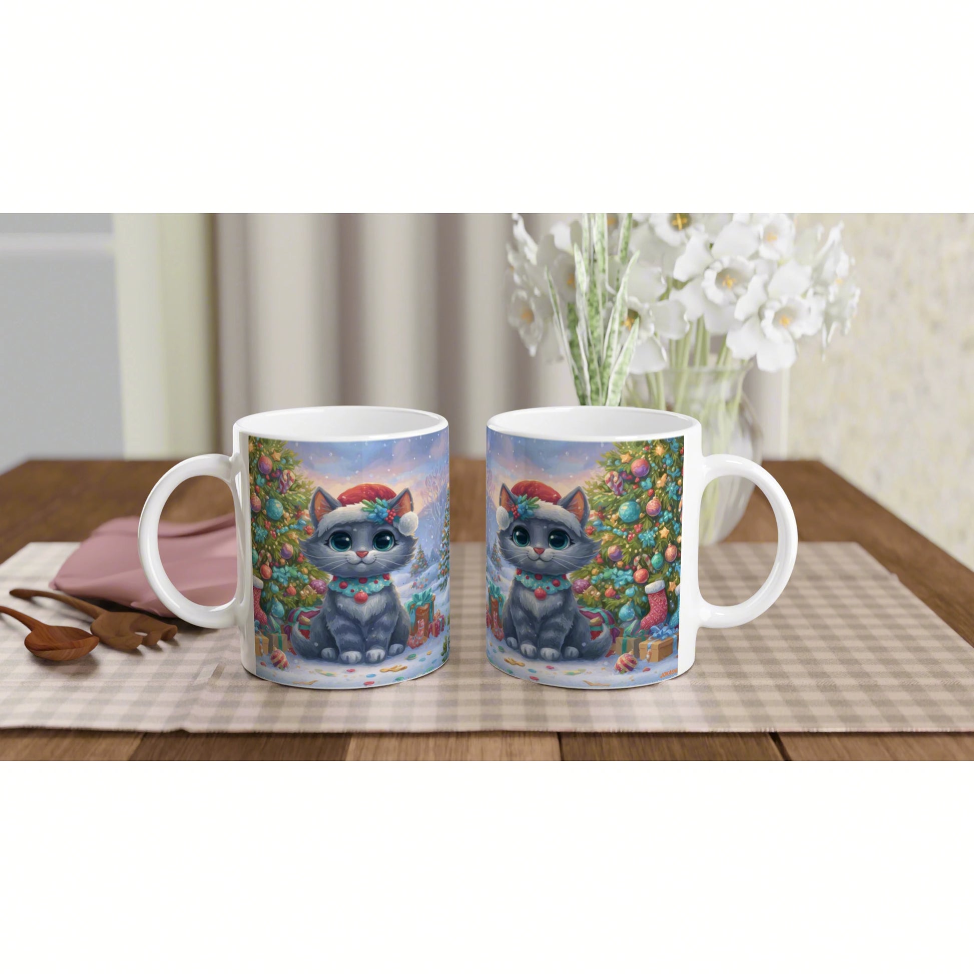 Two white mugs feature a cute gray cat wearing a Santa hat in a festive Christmas tree scene, set on a wooden table.