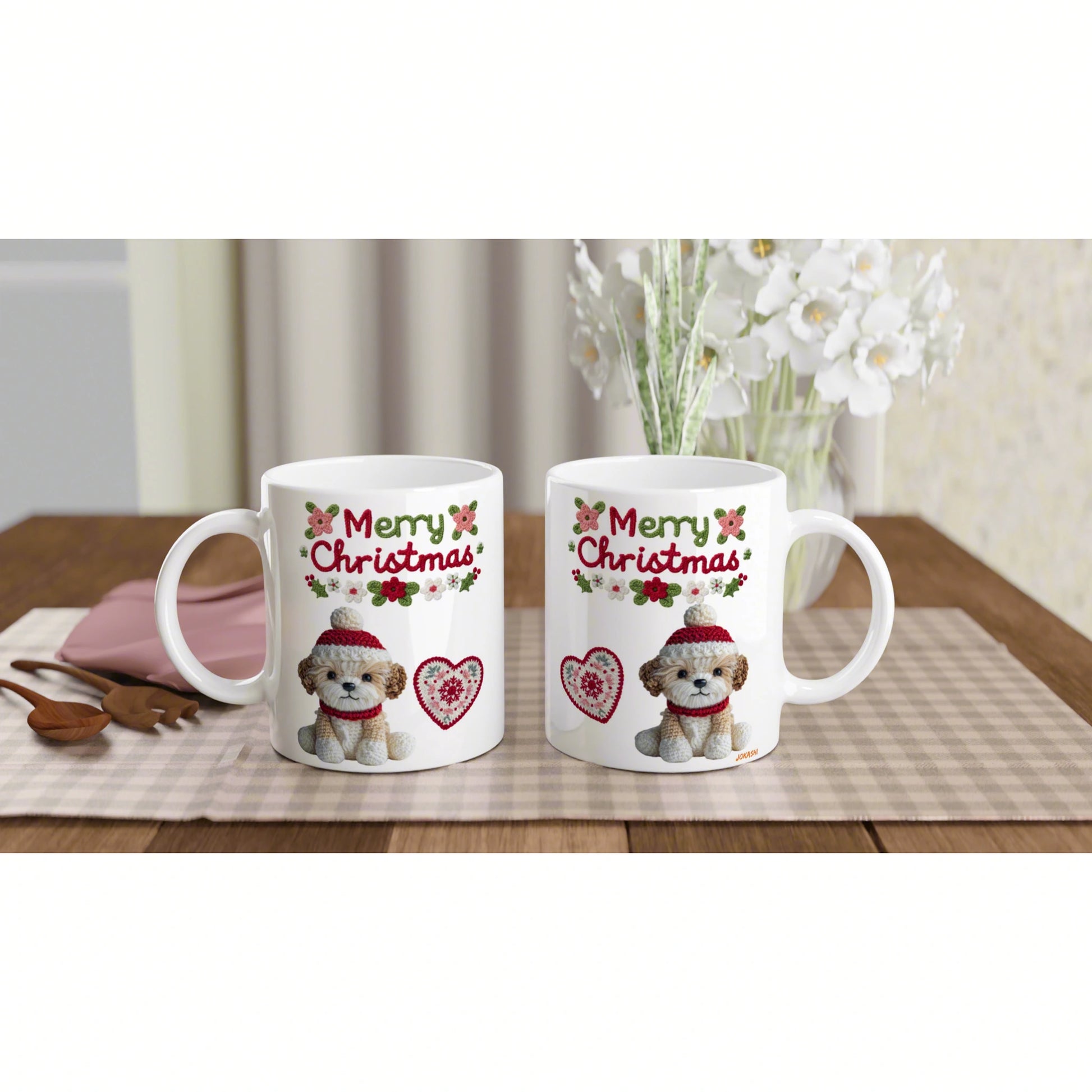 Two white mugs featuring a Christmas dog design with hearts on a plaid placemat, with blurred flowers in the background.