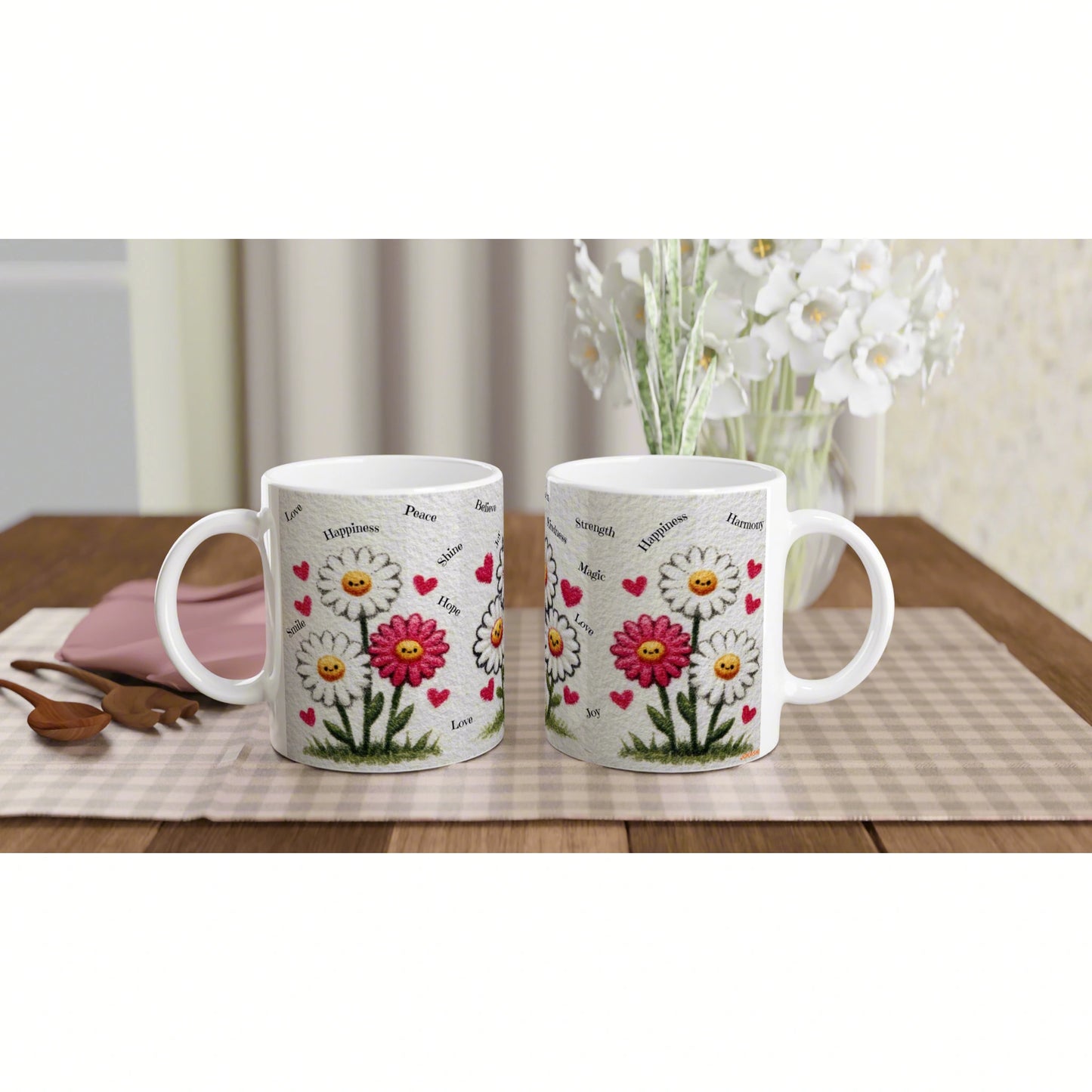 Two white mugs with a daisy and heart design, shown as a product mockup on a beige checkered mat atop a wooden table.