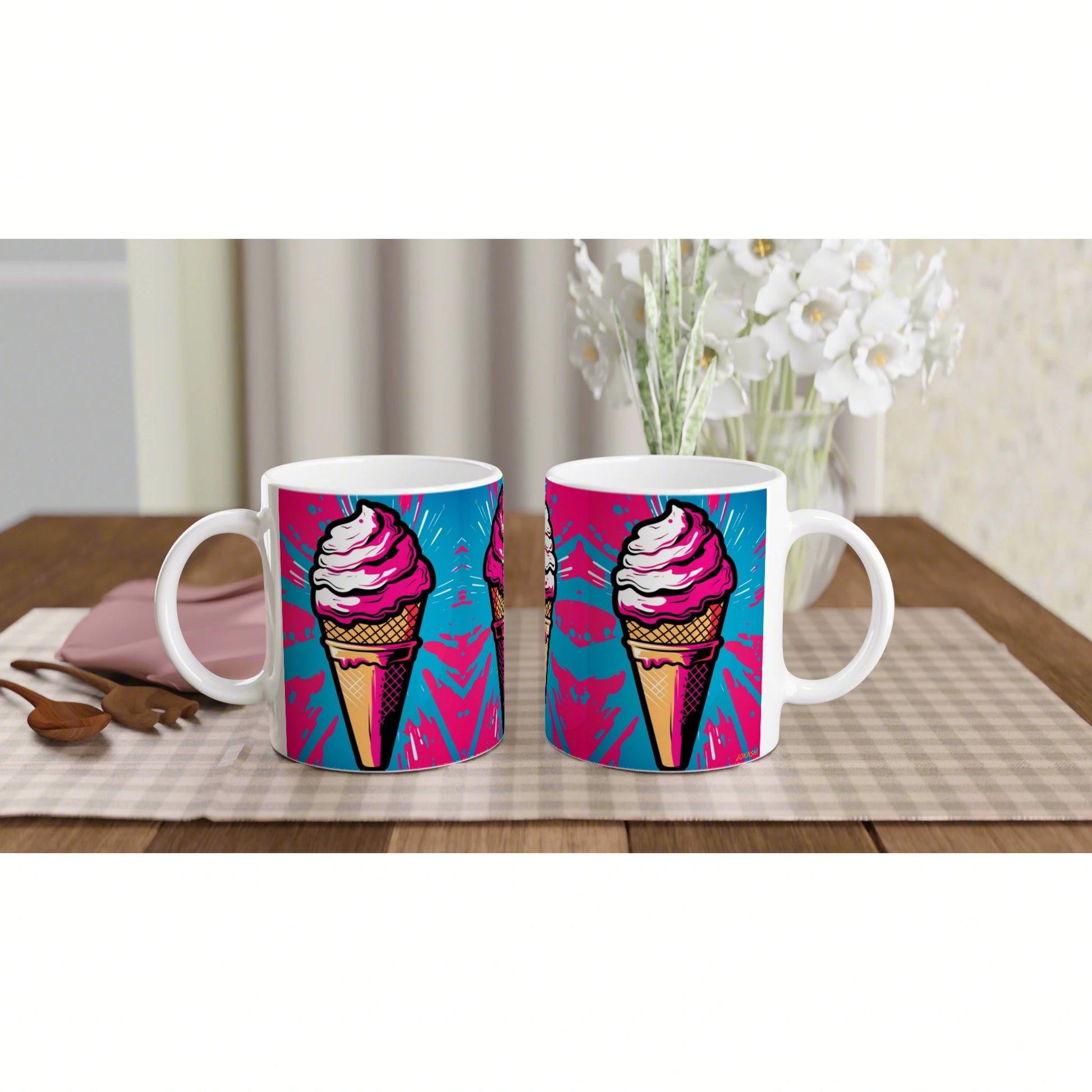 Two white mugs with a bright pink ice-cream cone graphic on a blue-magenta background, set on a wooden table with a placemat.