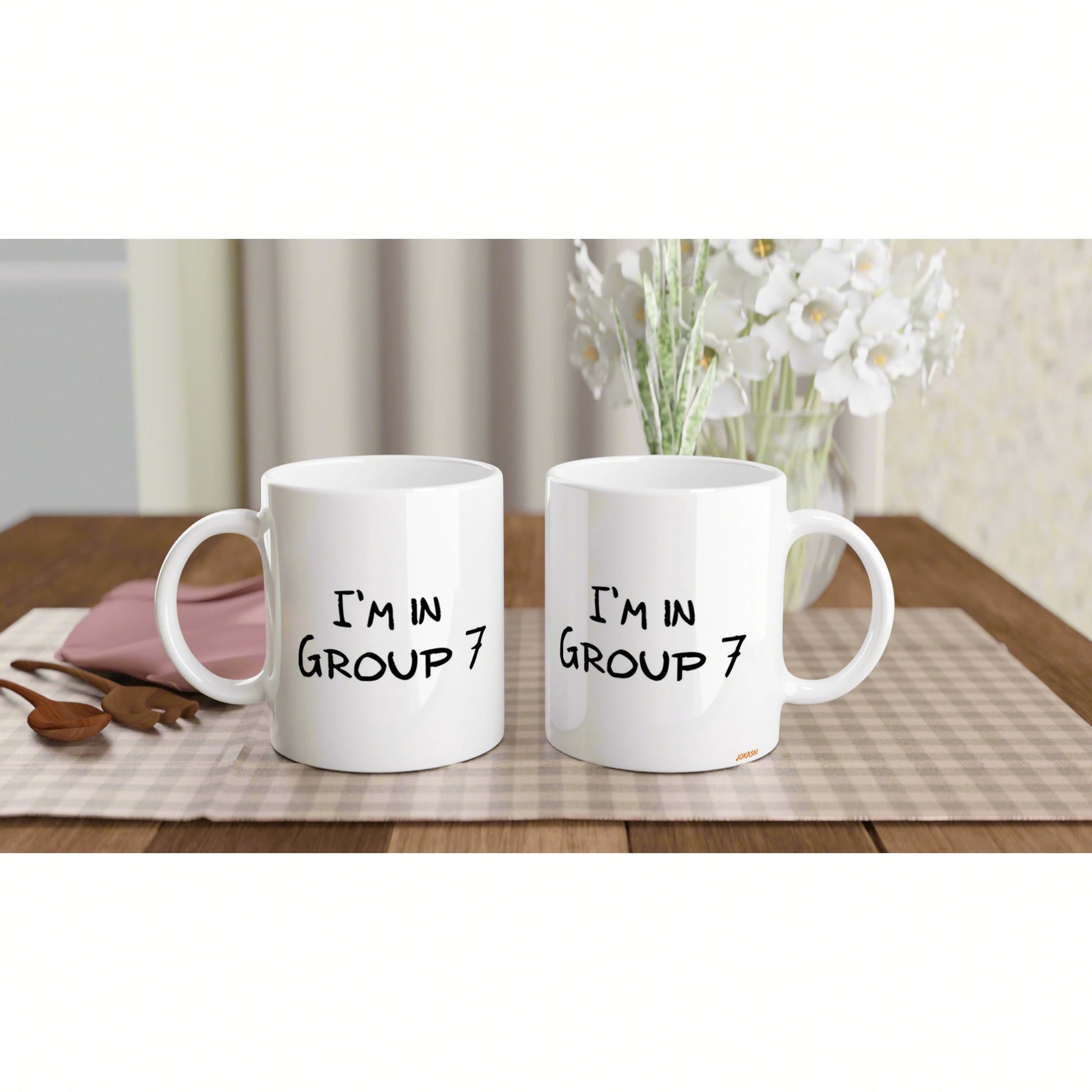 Two white ceramic mugs on a wooden table with the text I'M IN GROUP 7, shown as a product mockup for humorous mugs.