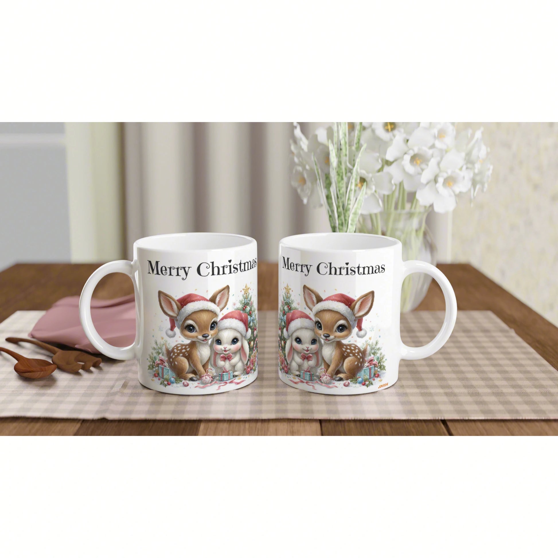 Two white mugs with 'Merry Christmas' and a festive deer and bunny illustration wearing Santa hats on a plaid placemat.