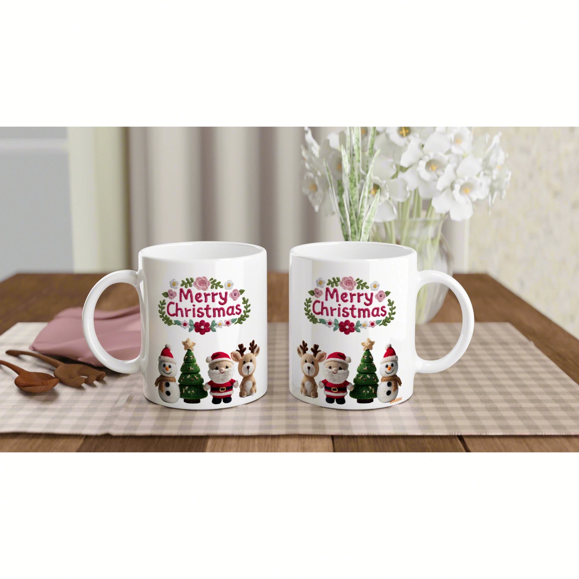 Two white mugs with a 'Merry Christmas' design featuring Santa, snowman, reindeer and Christmas trees on a beige checkered placemat.
