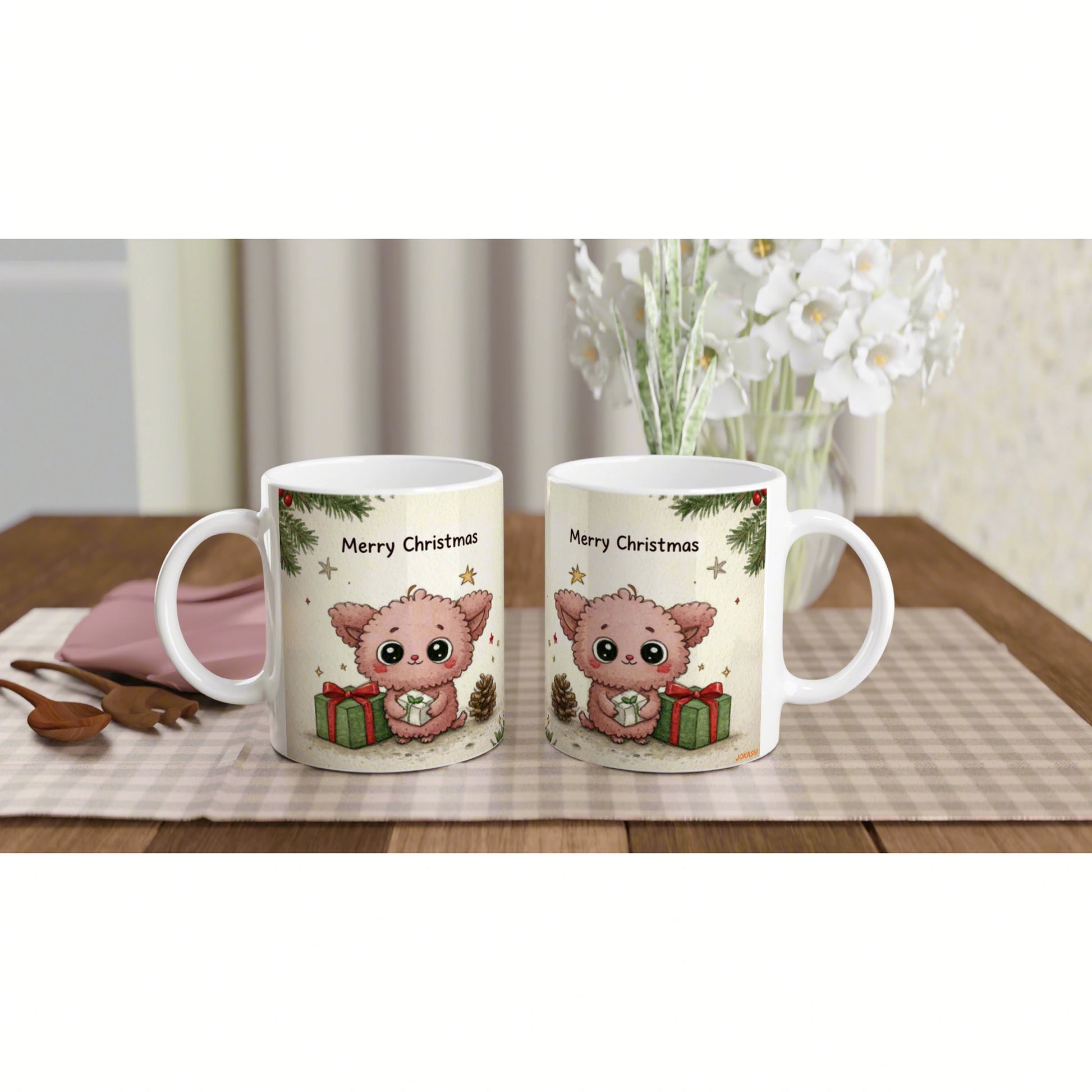 Two white mugs showing a cute pink kitten, 'Merry Christmas' design, and gift boxes on a beige checkered table runner.