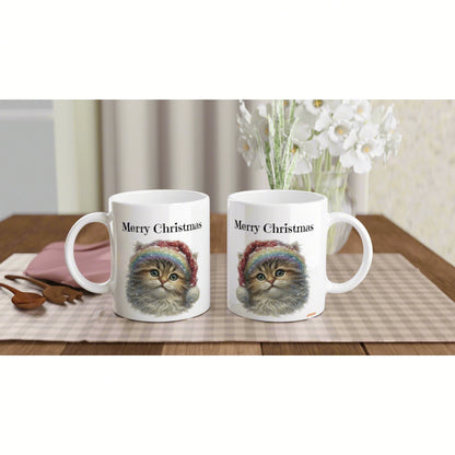 Two white mugs with 'Merry Christmas' and a fluffy kitten in a rainbow hat, product mockup on a wooden table.