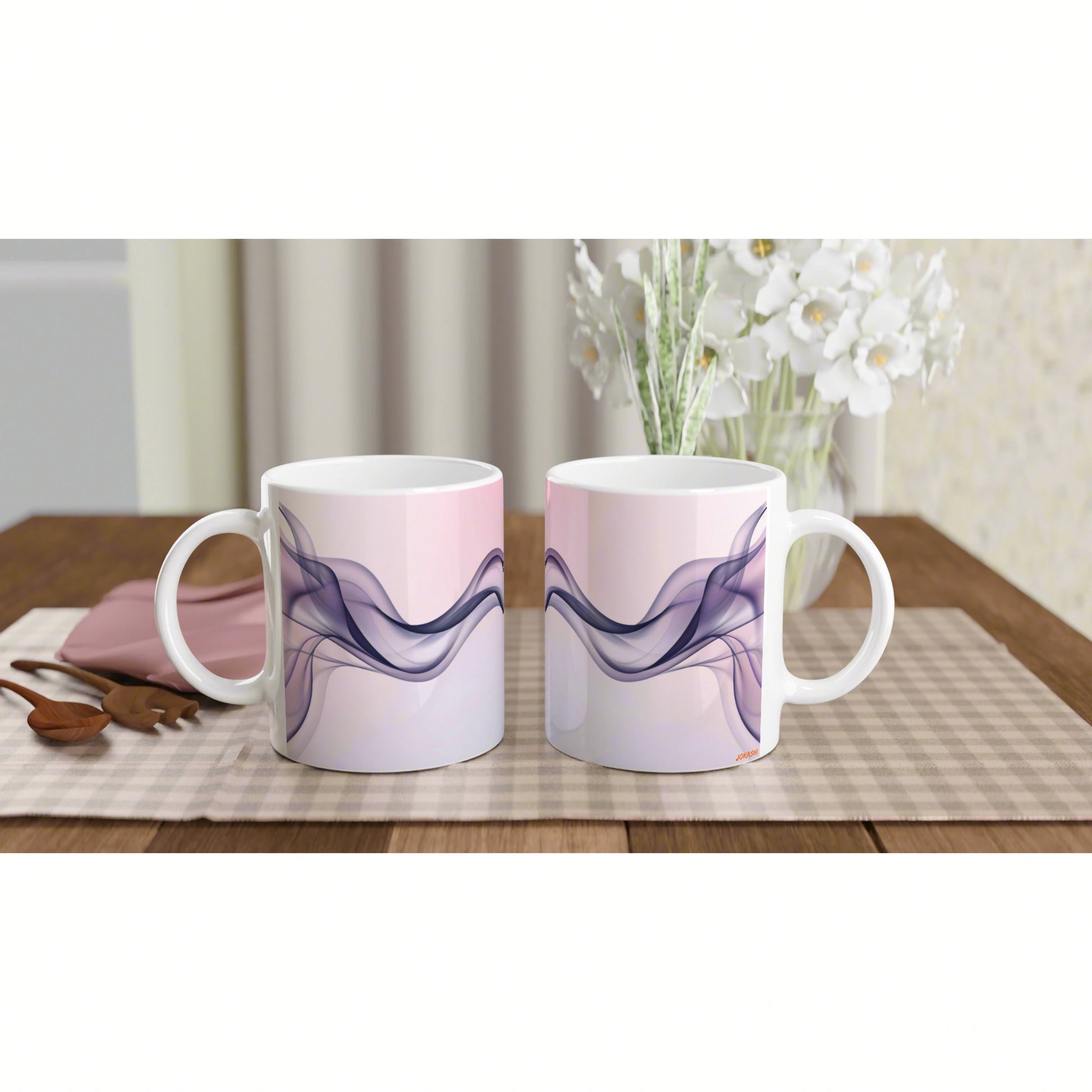 Two white mugs with pink gradient and purple wavy design on a checkered placemat; wooden table with white flowers behind.