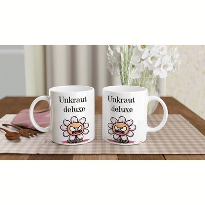 Two white mugs featuring the text Unkraut deluxe and a cartoon angry flower, on a checkered placemat on a wooden table.