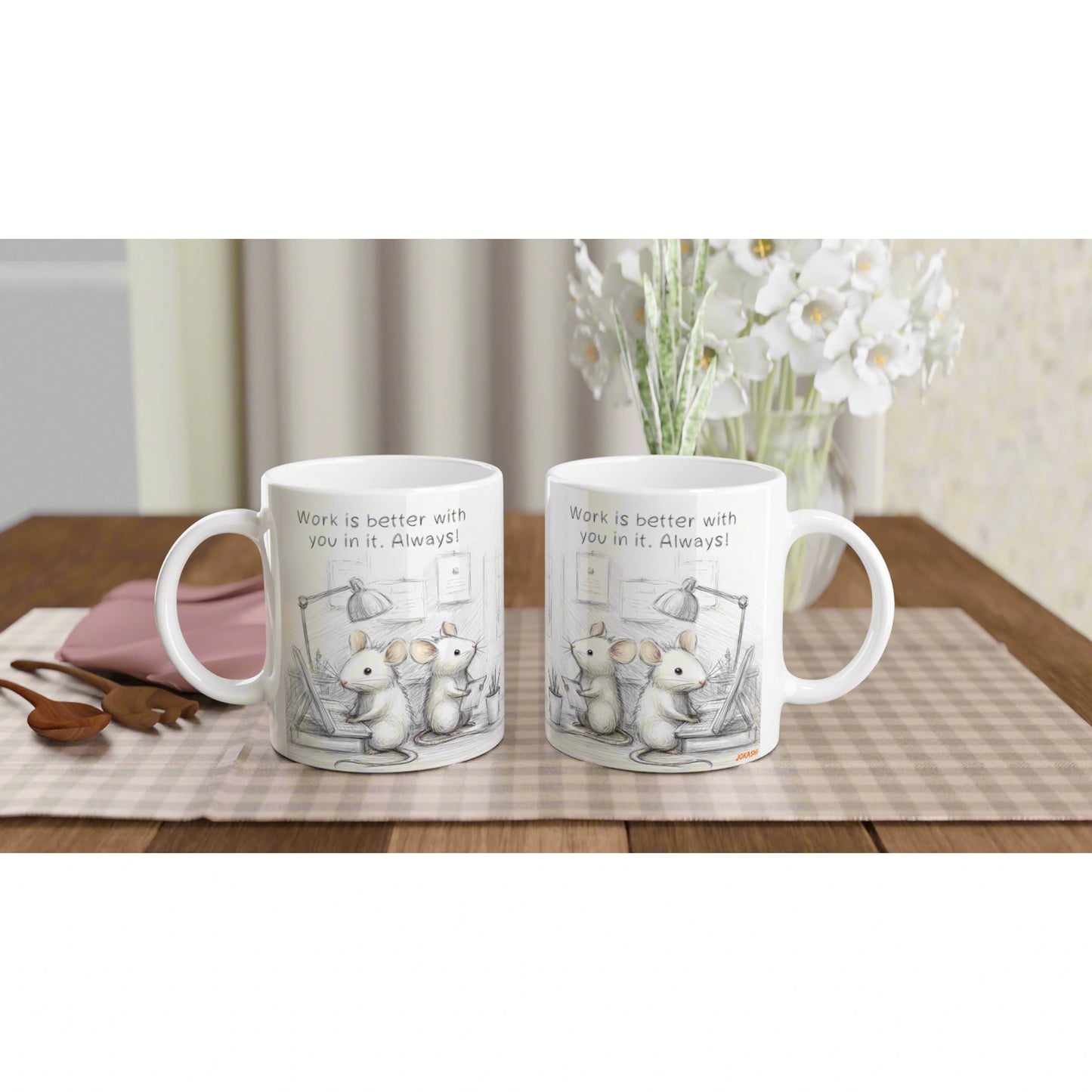 Two white mugs with a mouse illustration and the slogan 'Work is better with you in it. Always!', on a checkered placemat.