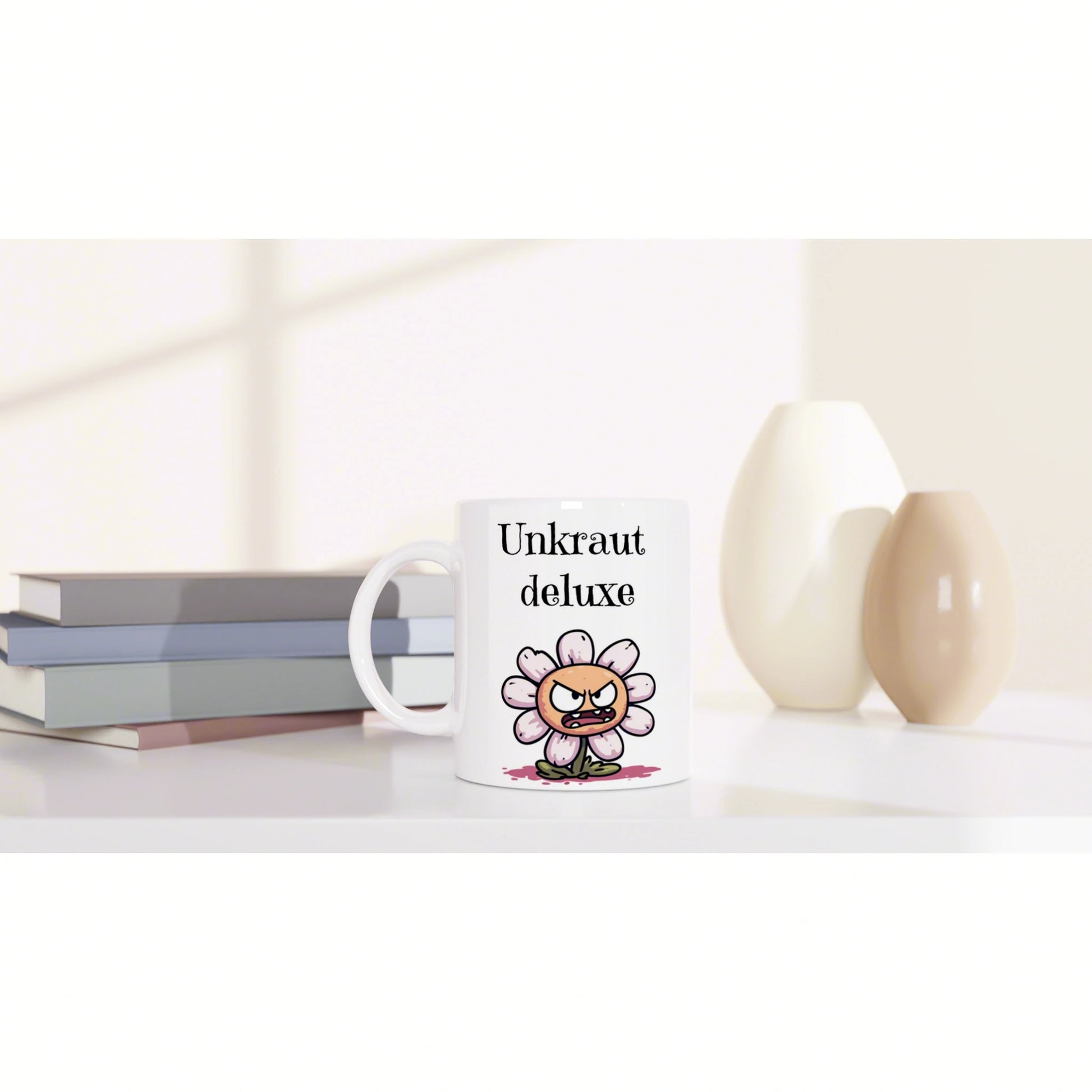 White mug with 'Unkraut deluxe' slogan and a cartoon angry flower, placed beside stacked books and beige ceramic vases.
