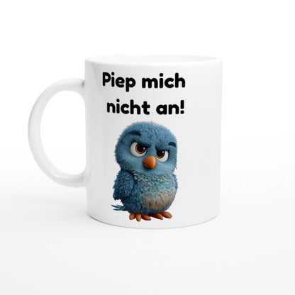 Weiße Tasse mit blauem, flauschigem Cartoonvogel und dem Spruch 'Piep mich nicht an!'