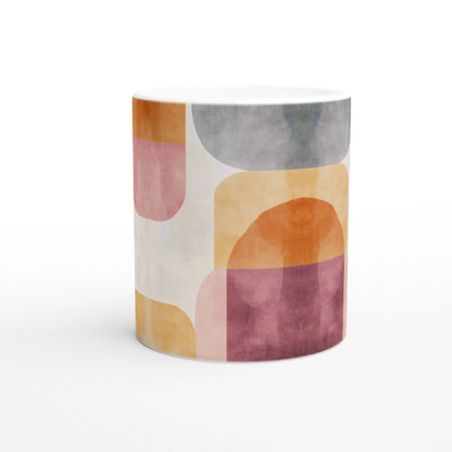 White ceramic mug with an abstract pastel pattern of orange, pink, yellow and gray geometric shapes; a modern product mockup.