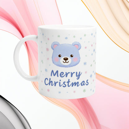 White ceramic mug featuring a blue teddy bear face and 'Merry Christmas' text with pastel snowflakes; product mockup.