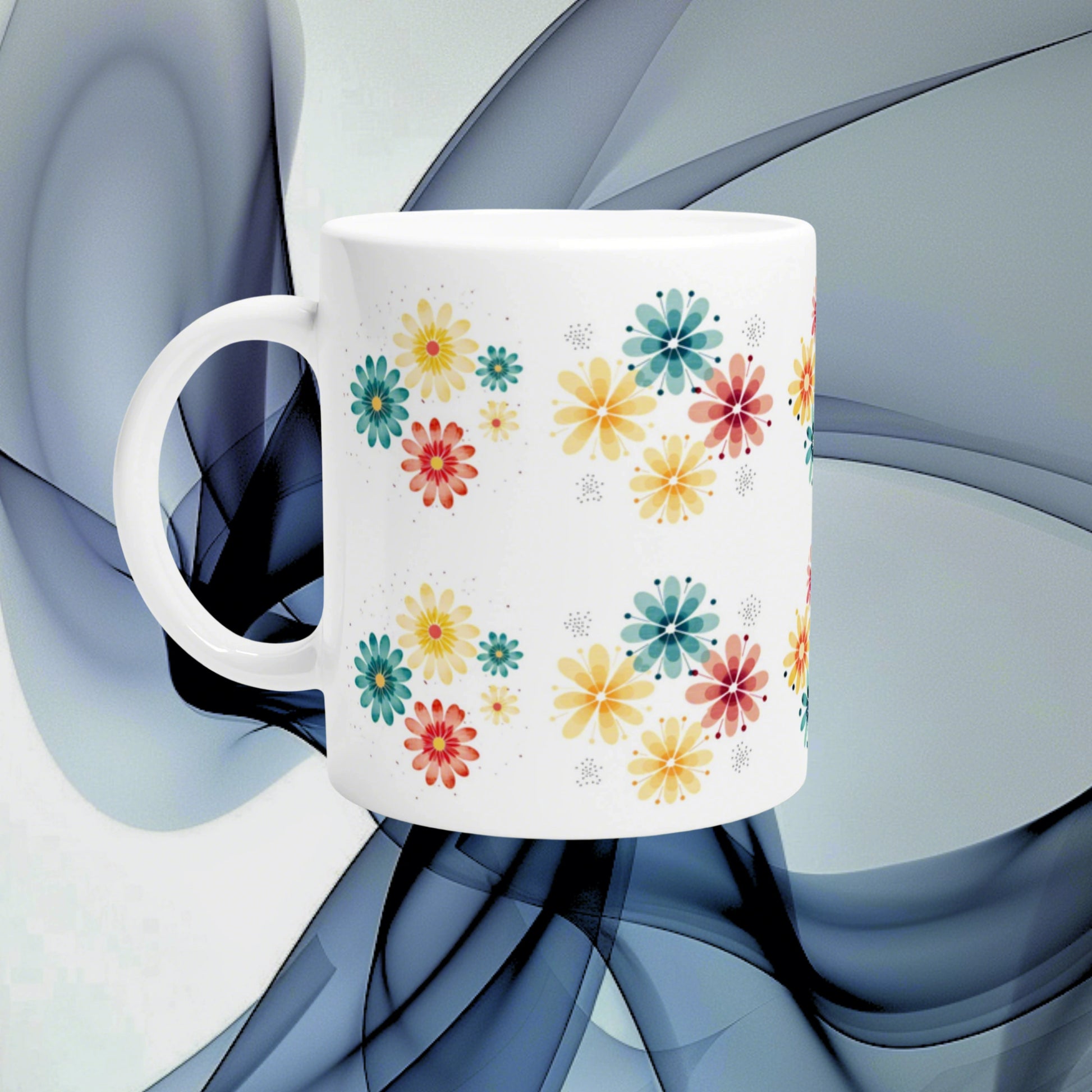 White ceramic mug featuring a vivid multicolor floral pattern with yellow, teal, orange and pink flowers on a white background.