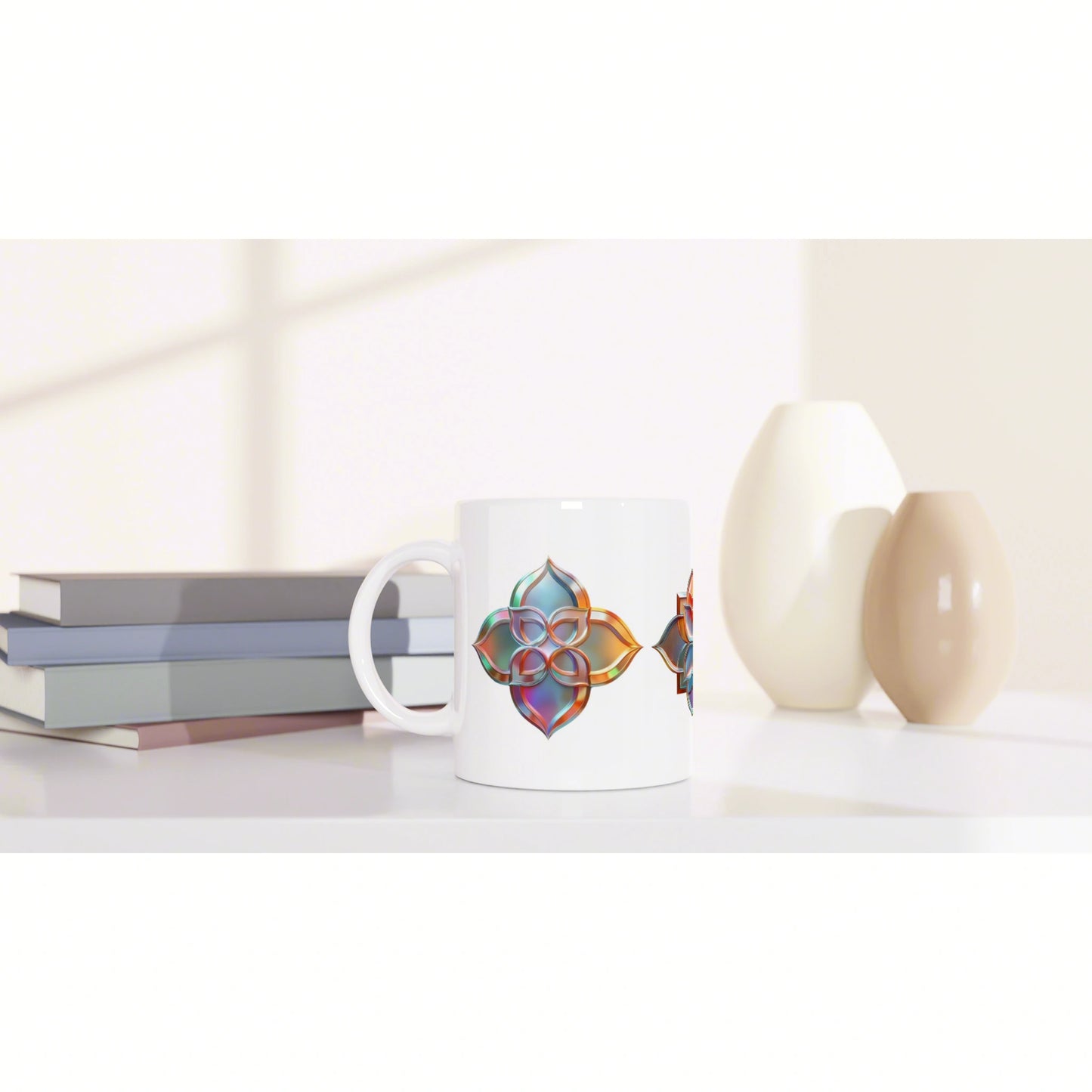 White ceramic mug with a colorful geometric pattern, shown as a product mockup on a desk with books and beige vases.