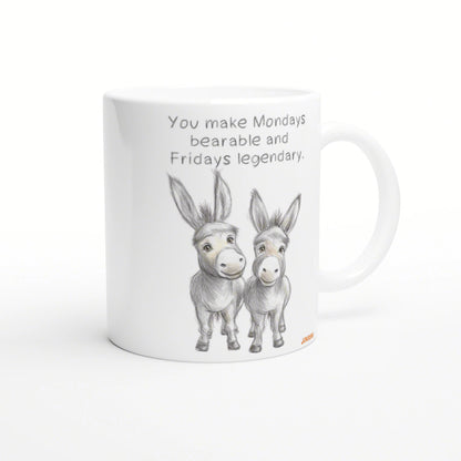 White ceramic mug mockup with a pencil sketch of two donkeys and the slogan You make Mondays bearable and Fridays legendary.