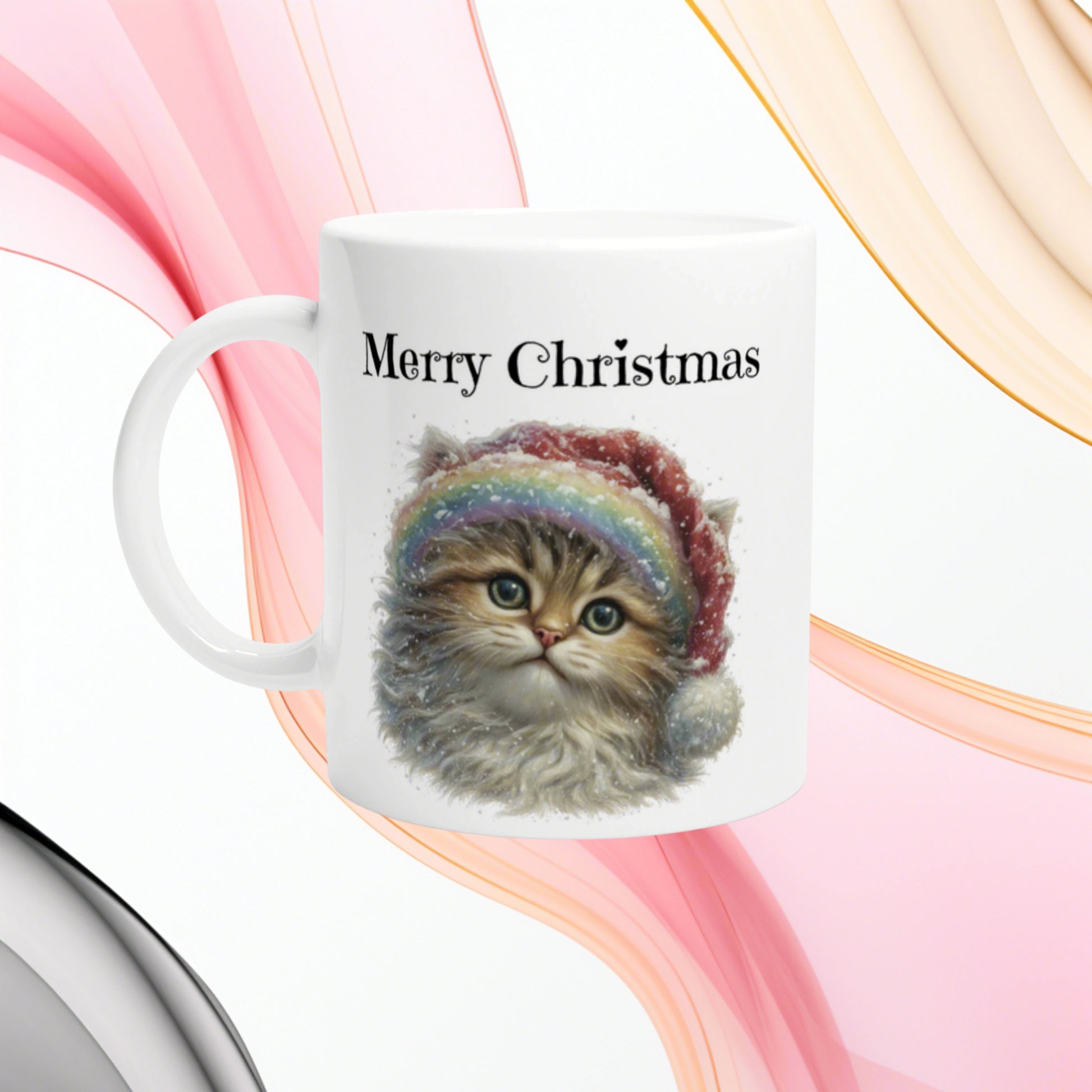 White ceramic mug featuring a cute kitten wearing a rainbow Santa hat and the text Merry Christmas.