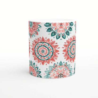 White ceramic mug with mandala-inspired floral patterns in coral and teal; product mockup.