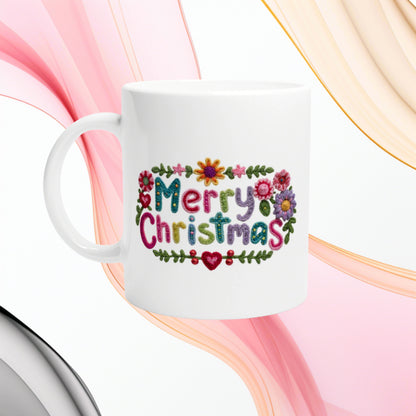 White ceramic mug with a colorful embroidered 'Merry Christmas' design and floral border; product mockup.