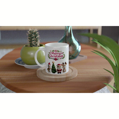 White ceramic mug with a 'Merry Christmas' floral wreath and cute holiday characters on a wooden table (product mockup).