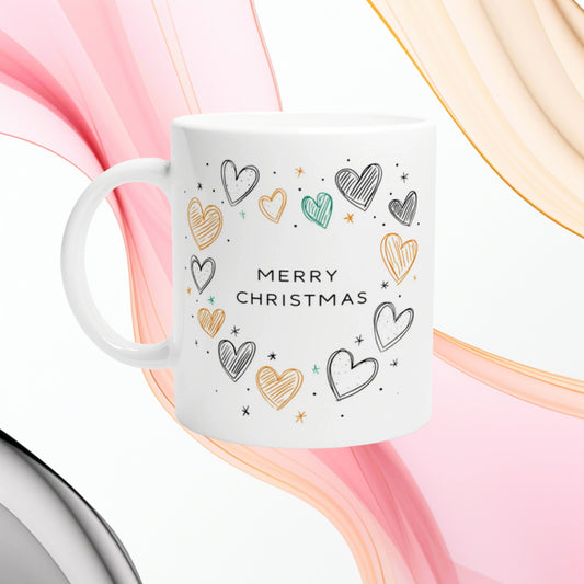 White ceramic mug featuring a 'MERRY CHRISTMAS' slogan with hand-drawn colorful hearts; product mockup for a holiday gift shop.