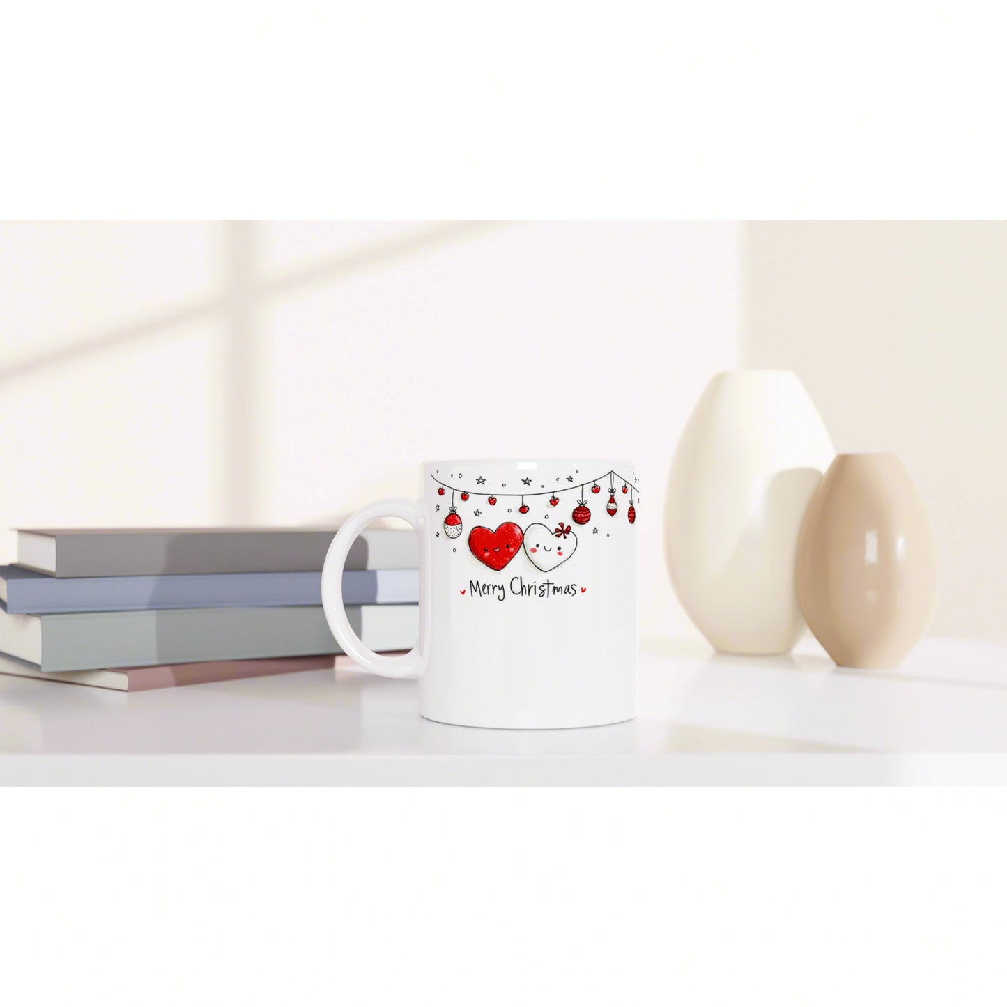 White ceramic mug with a Merry Christmas design featuring red hearts and hanging string lights, beside books and vases.