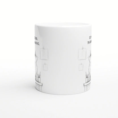 White ceramic mug mockup with a subtle pencil-sketch desk scene and small frames.