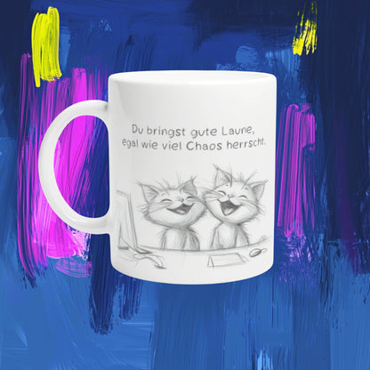 White ceramic mug mockup showing two laughing cats in a pencil sketch and a German slogan about good mood amid chaos