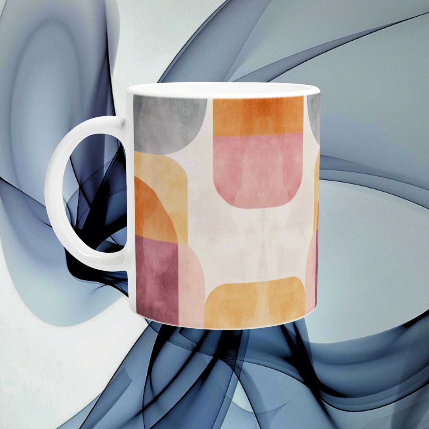 White ceramic mug featuring a pastel abstract geometric pattern in pink, peach, yellow, and gray on a blue backdrop.