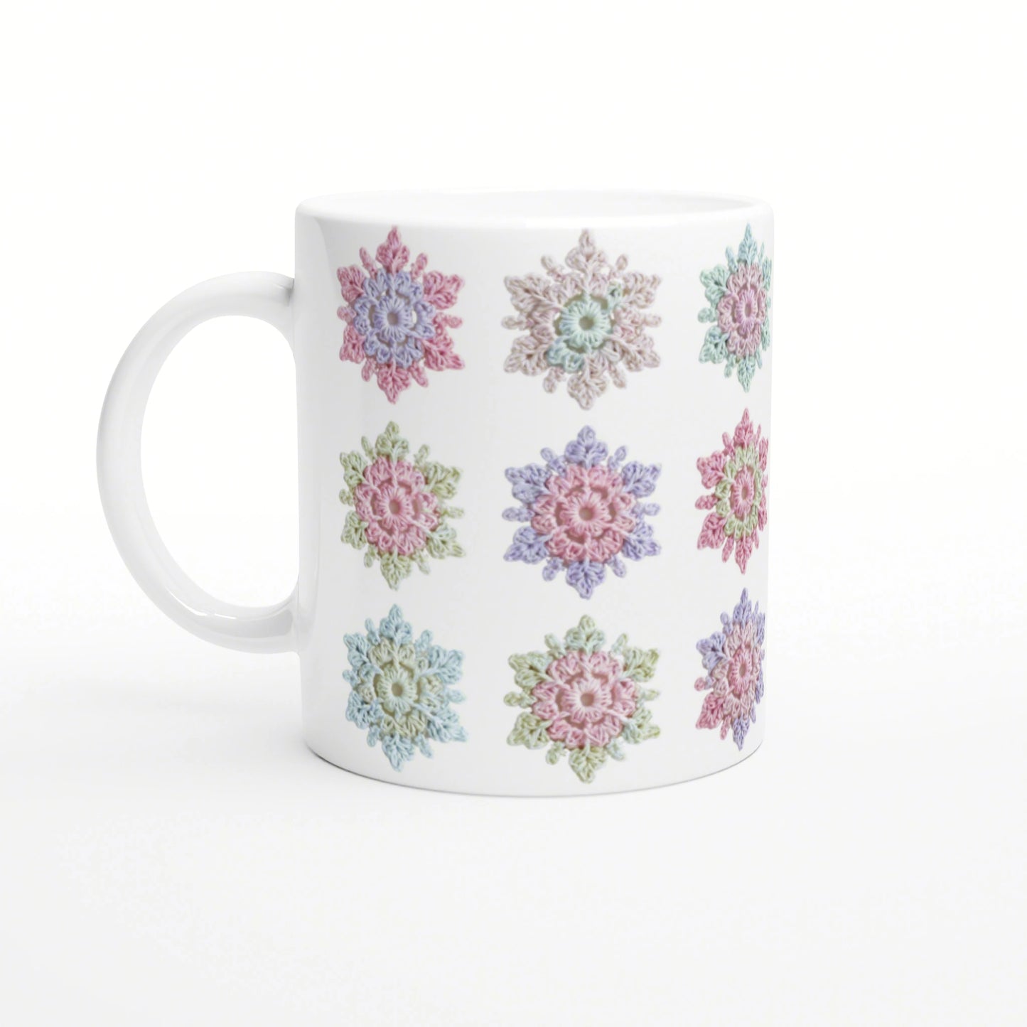 White ceramic mug with a repeating pattern of pastel crochet-style flowers.