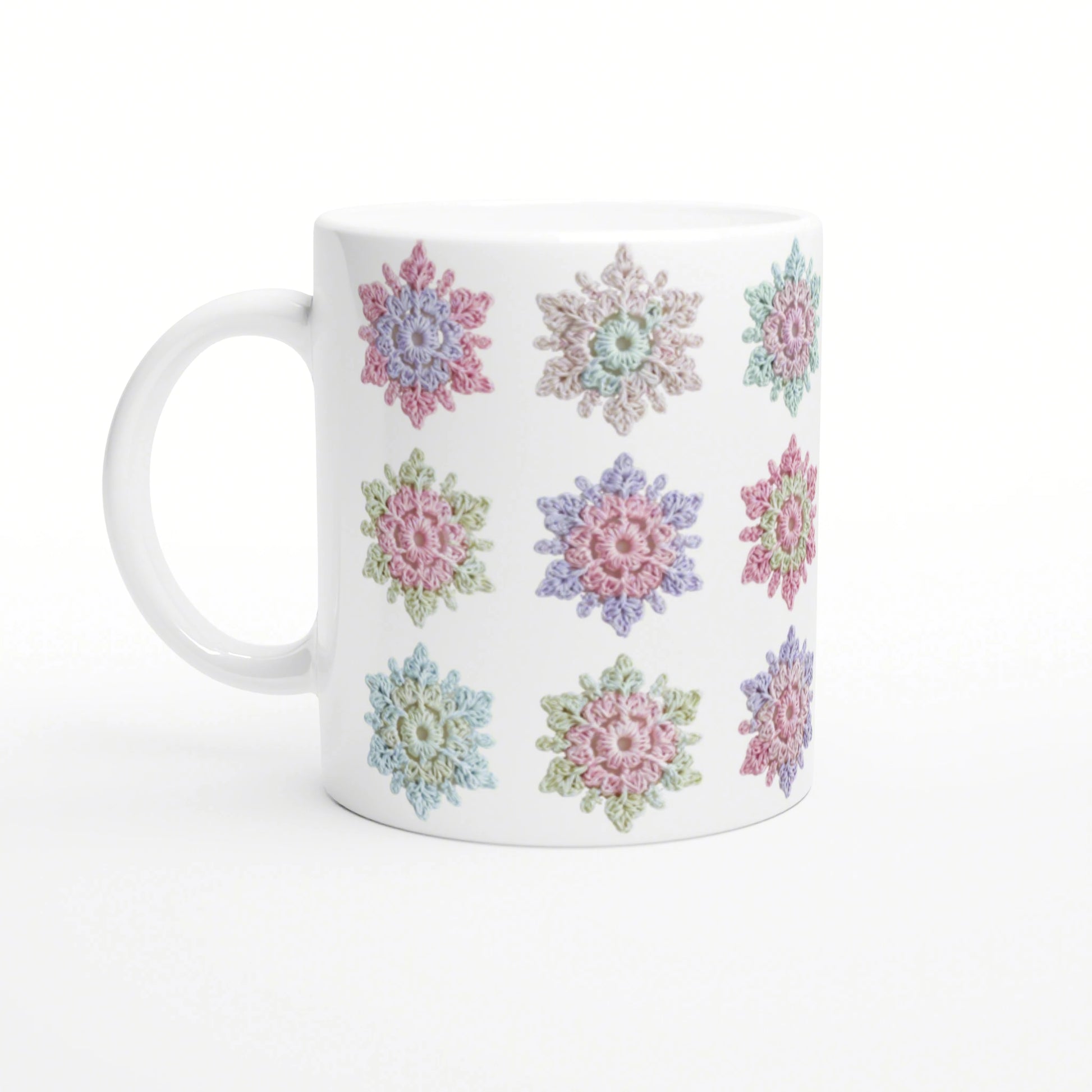 White ceramic mug with a repeating pattern of pastel crochet-style flowers.