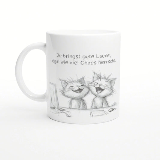 White ceramic mug featuring a pencil sketch of two laughing cats and a German caption about good mood despite chaos.