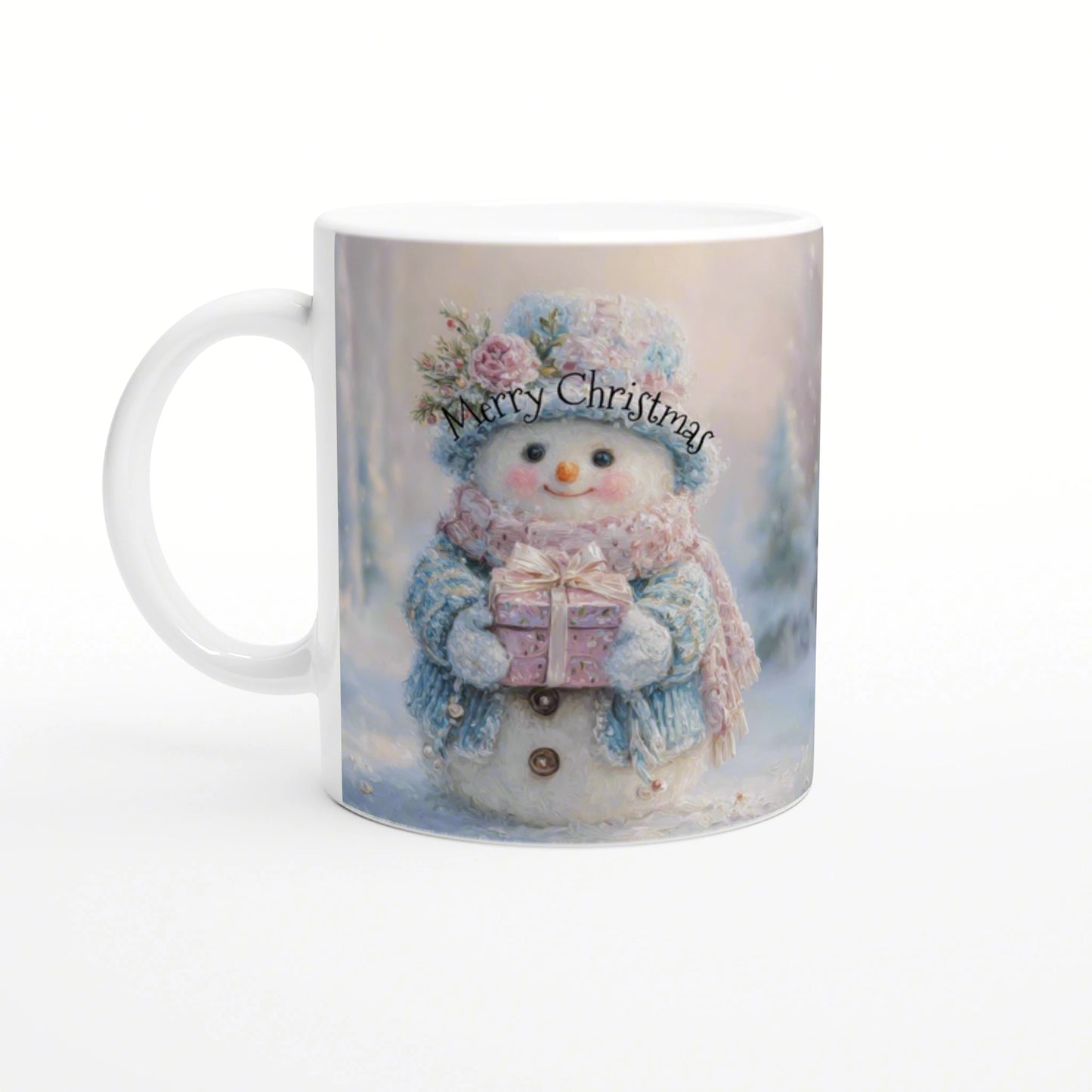 White ceramic mug showing a snowy Christmas scene: a smiling snowman in a blue scarf and pink hat holding a gift, Merry Christmas text.