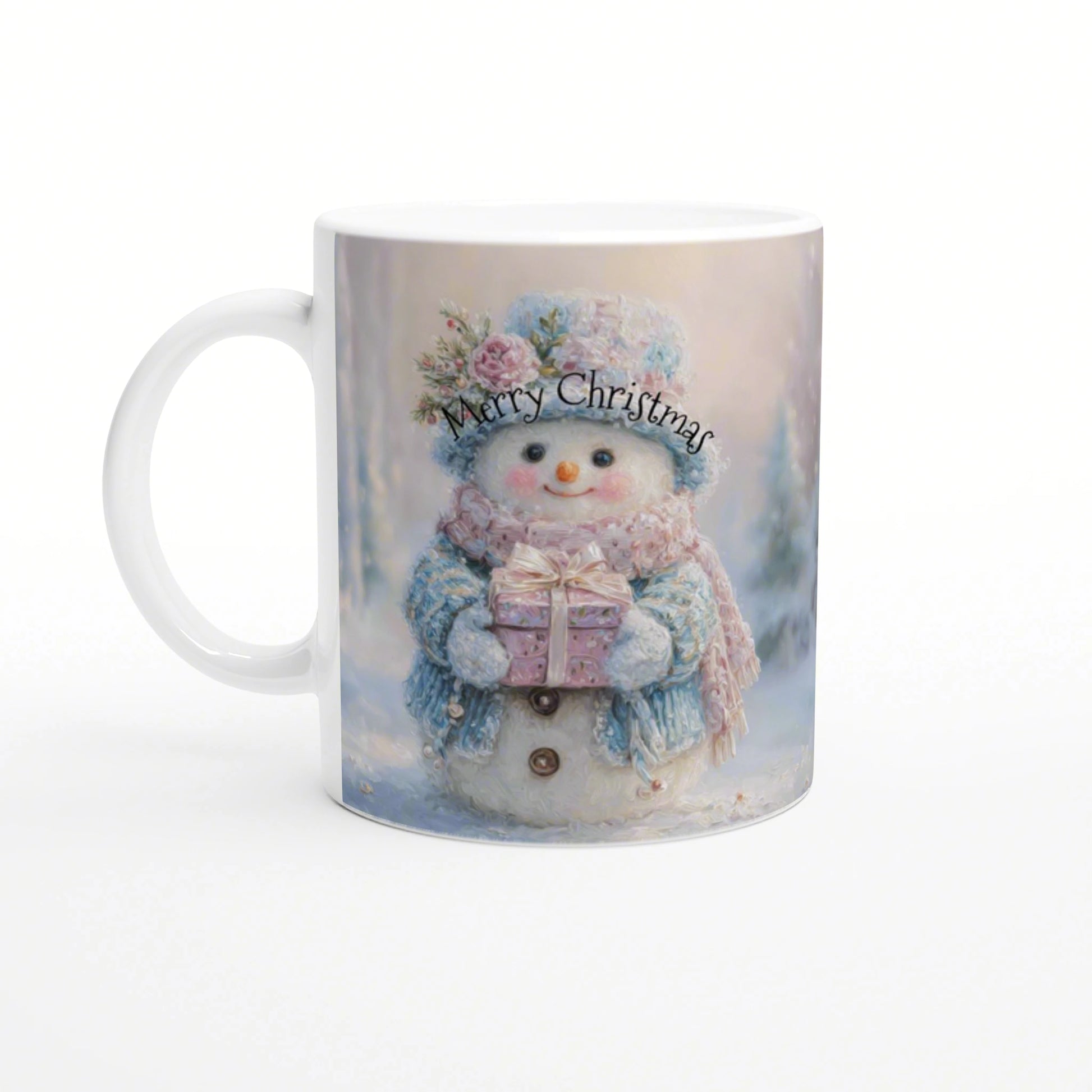 White ceramic mug showing a snowy Christmas scene: a smiling snowman in a blue scarf and pink hat holding a gift, Merry Christmas text.