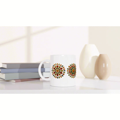 White ceramic mug with two colorful circular mandala designs, placed on a shelf beside stacked books and decorative vases.