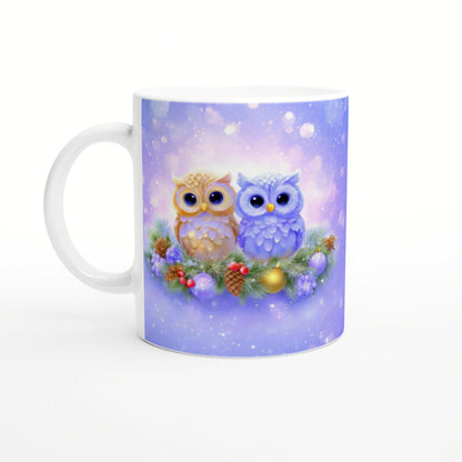 White ceramic mug with pastel purple winter scene: two cute owls perched on a festive wreath with pine cones and ornaments.