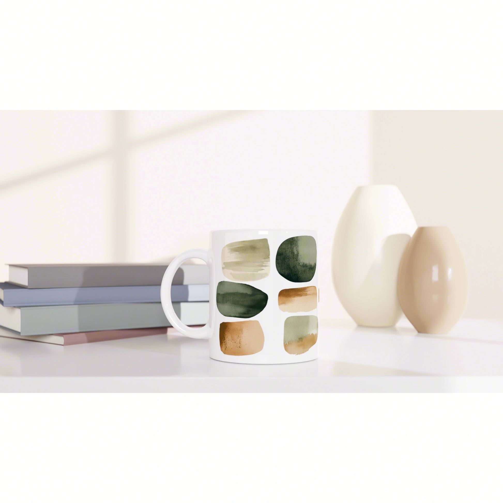 White mug with abstract brushstroke squares sits on a shelf beside books and two ceramic vases.