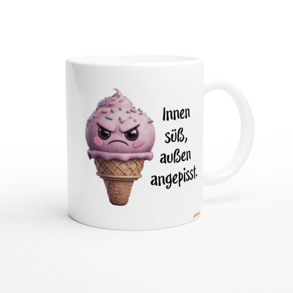 White mug featuring a pink, angry ice-cream cone with sprinkles, alongside the German text Innen süß, außen angepisst.