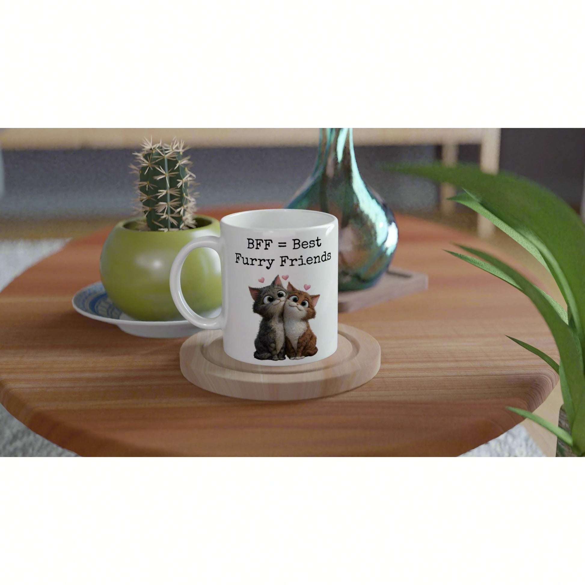 White mug with 'BFF = Best Furry Friends' and two cats, on a wooden coaster beside a cactus and green vase.