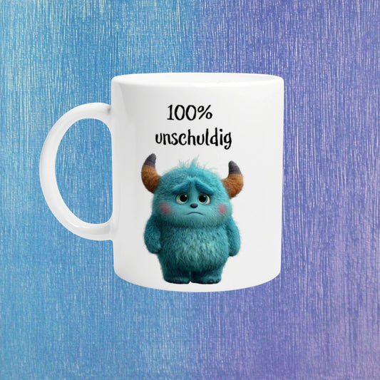 White ceramic mug featuring a blue fluffy monster with horns and the caption '100% unschuldig' on a blue-purple gradient background.