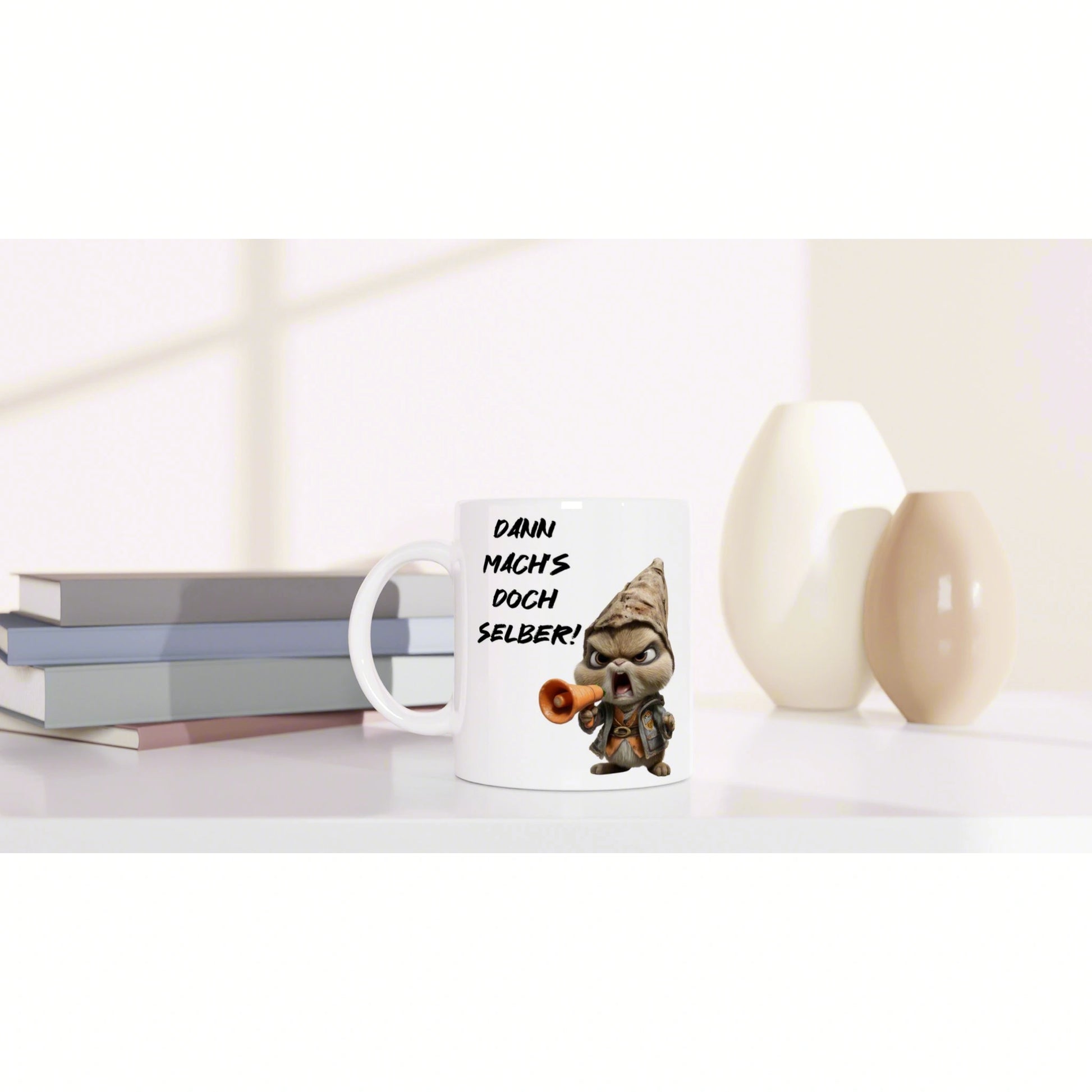 White mug with a cartoon gnome and megaphone, displaying the German slogan DANN MACHS DOCH SELBER!, on a desk with books.