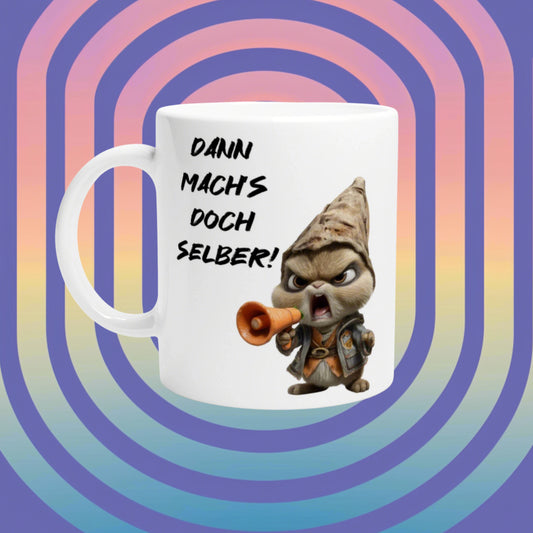 White mug with a cartoon gnome shouting into a megaphone and the slogan Dann mach's doch selber!, on a retro rainbow spiral background.