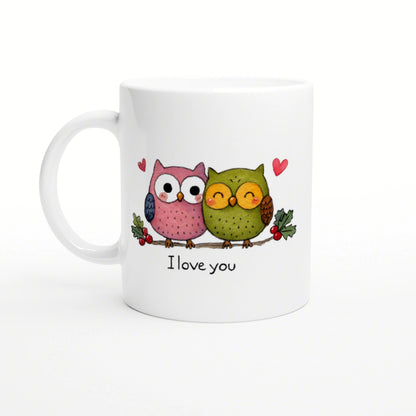 White mug with a cartoon pink and green pair of owls on a branch, with hearts and the text 'I love you'.