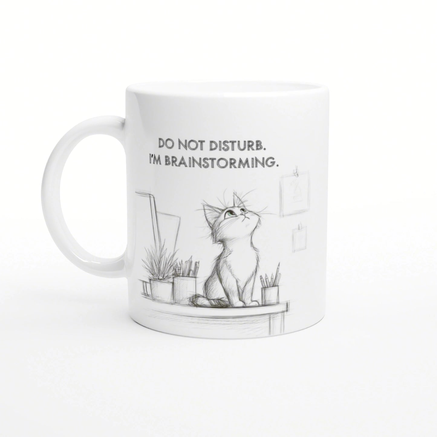White mug with a pencil-sketch cat on a desk, plants nearby, and the slogan DO NOT DISTURB. I'M BRAINSTORMING.
