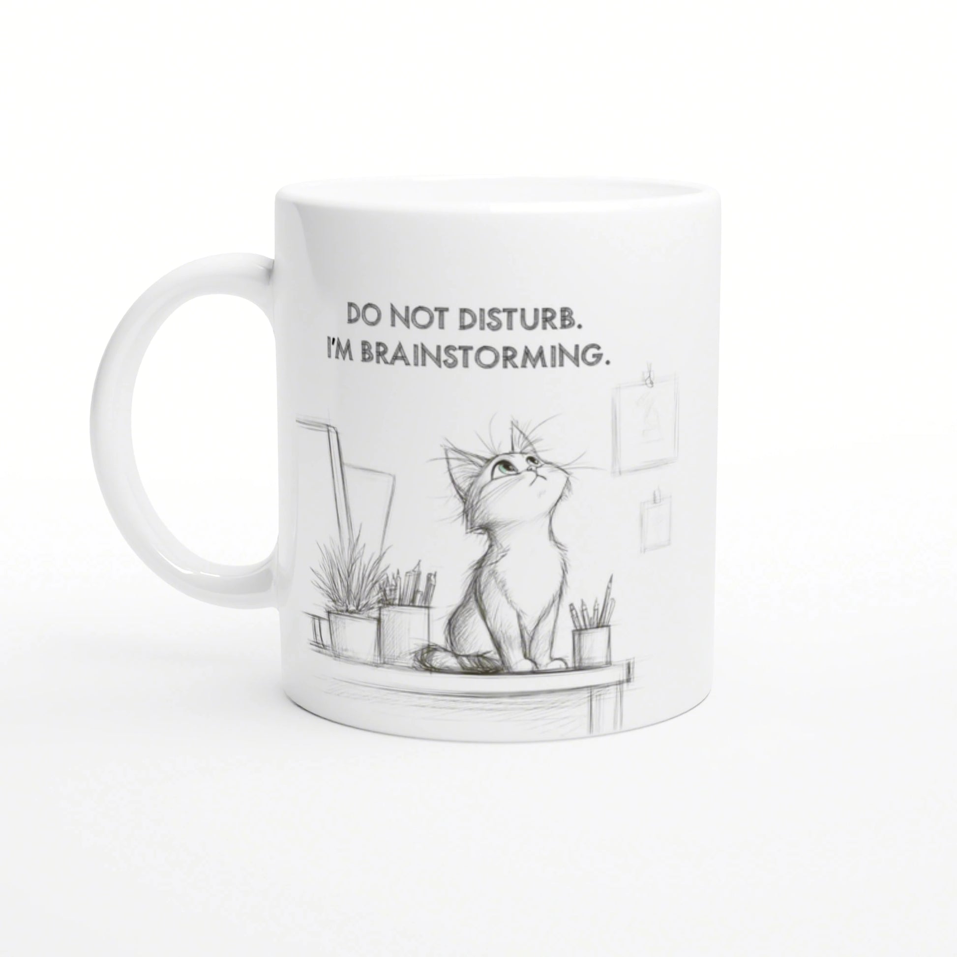 White mug with a pencil-sketch cat on a desk, plants nearby, and the slogan DO NOT DISTURB. I'M BRAINSTORMING.